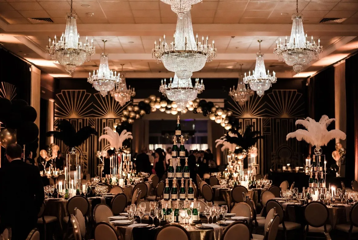 אווירת ערב גטסבי — אולם מעוצב בזהב ושחור עם נברשות ואורחים בבגדי תקופה