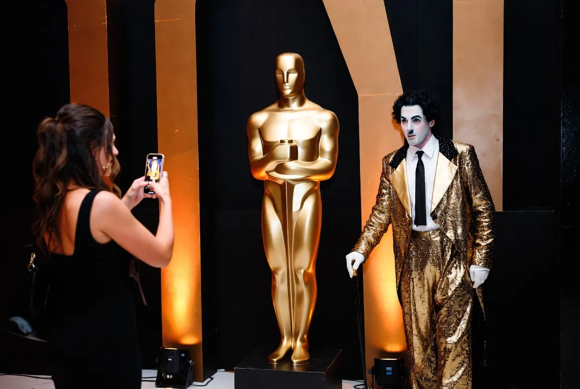 מייצגים בתלבושות זהובות עומדים כפסלים חיים בכניסת אירוע הוליוודי