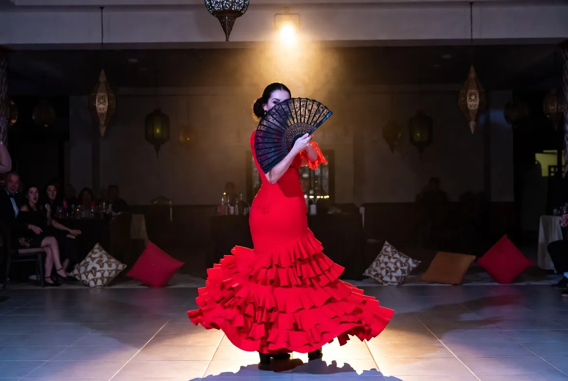 רקדנית פלמנקו בשמלה אדומה עם מניפה באירוע מזרחי — רגע דרמטי